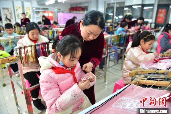 江西省級(jí)非遺豫章繡傳承人手把手指導(dǎo)小學(xué)生繡制2022年北京冬奧會(huì)吉祥物“冰墩墩”形象。　喻云亮 攝