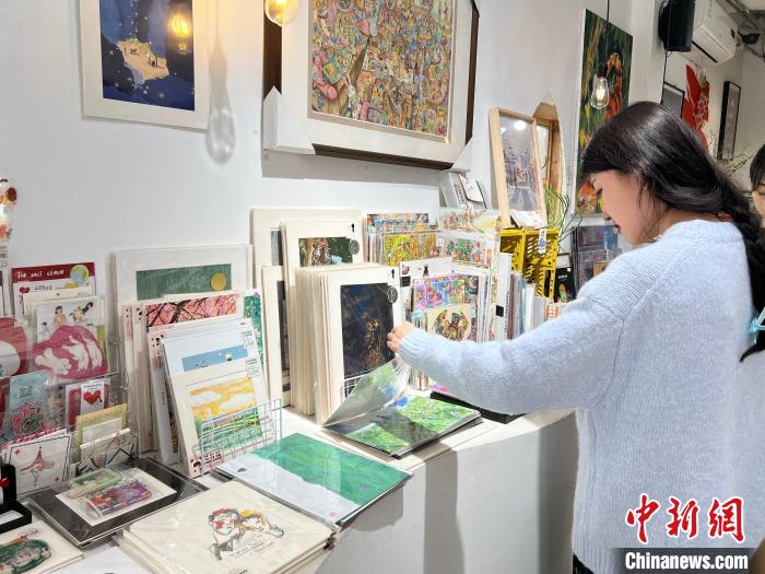 圖為藝術(shù)品商店內(nèi)，顧客挑選插畫作品。　鐘旖 攝