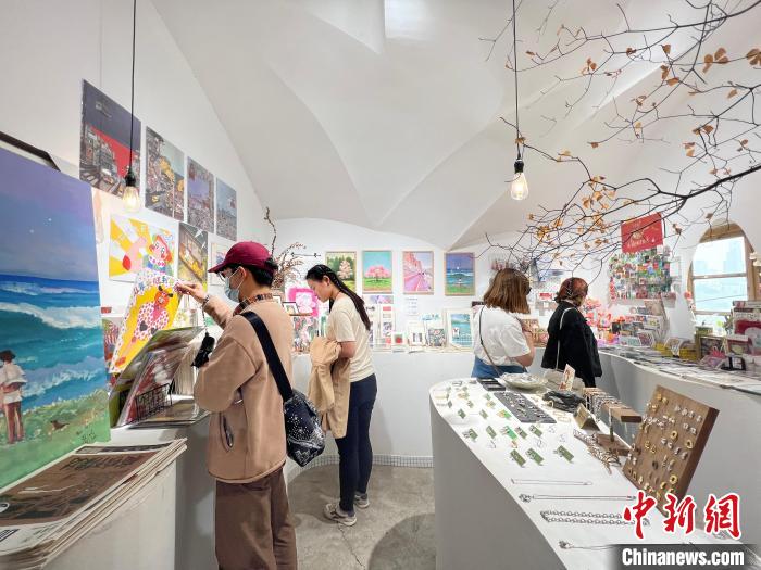 圖為藝術(shù)品商店內(nèi)，顧客挑選插畫作品?！＄婌?攝