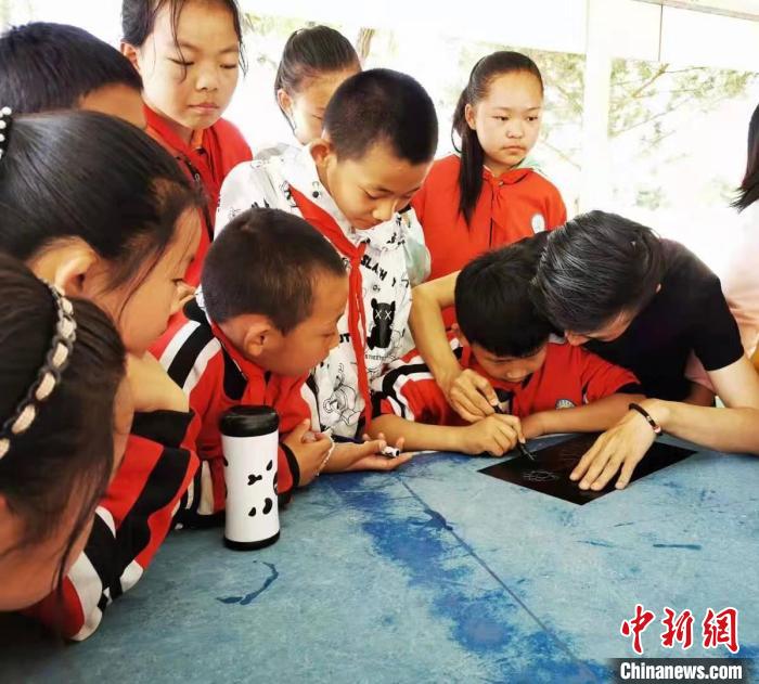 圖為朱增平(右一)教學(xué)生創(chuàng)作鍥金畫。(資料圖) 受訪者供圖