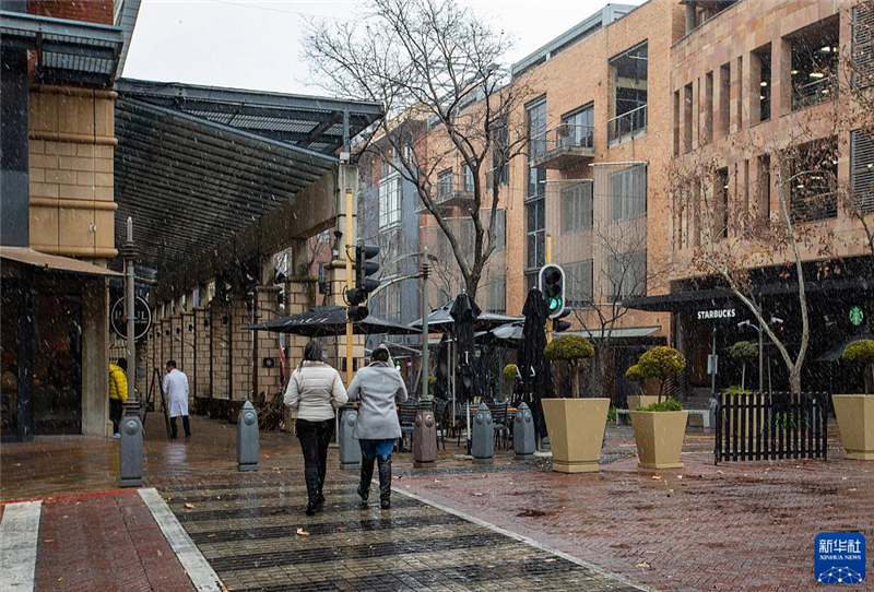 7月10日，在南非約翰內(nèi)斯堡一處商業(yè)區(qū)，人們在雪中行走。新華社記者 張譽東 攝