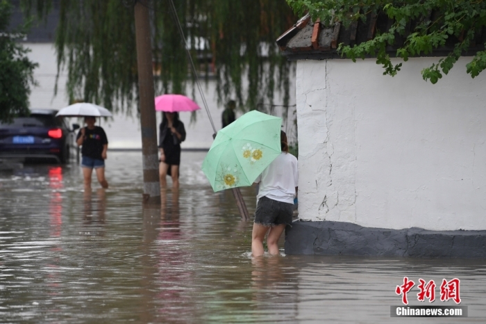 7月31日，市民行走在雨中的北京房山區(qū)瓦窯頭村。北京市氣象臺當(dāng)日10時發(fā)布分區(qū)域暴雨紅色預(yù)警信號。北京市水文總站發(fā)布洪水紅色預(yù)警，預(yù)計當(dāng)日12時至14時，房山區(qū)大石河流域?qū)⒊霈F(xiàn)紅色預(yù)警標(biāo)準(zhǔn)洪水。<a target='_blank' href='/'><p  align=