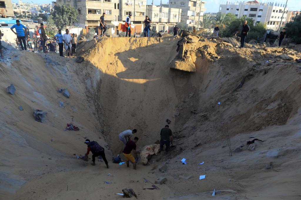 10月16日，在加沙地帶南部城市汗尤尼斯，人們在遭以色列襲擊后的建筑廢墟中救援傷者。 新華社發(fā)（亞西爾·庫迪 攝）