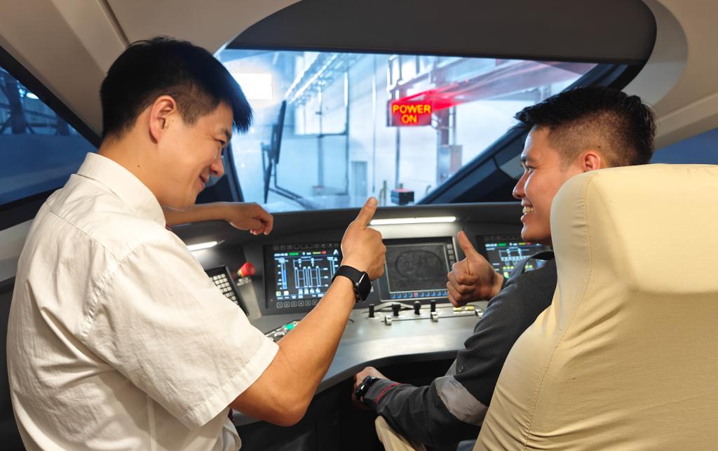 8月25日，在印度尼西亞萬隆的雅萬高鐵德卡魯爾動車所內(nèi)，中國師傅穆振（左）在向印尼火車司機(jī)塞蒂亞萬講解動車組出庫前的上電作業(yè)。