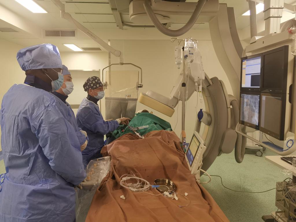 中國第29批援幾內(nèi)亞醫(yī)療隊隊員、首都醫(yī)科大學(xué)附屬北京天壇醫(yī)院心內(nèi)科副主任醫(yī)師王汝朋（右一）正在給患者做手術(shù)。（北京天壇醫(yī)院供圖）