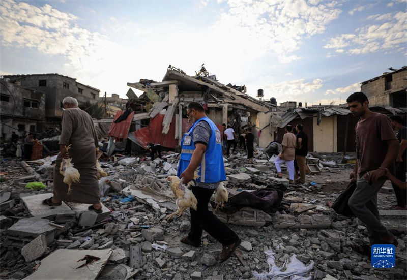10月27日，在加沙地帶南部城市汗尤尼斯，人們經(jīng)過以軍襲擊后的房屋廢墟。