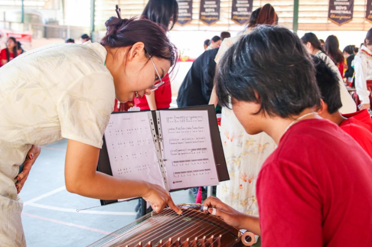 志愿者教師指導(dǎo)學(xué)生彈奏古箏。活動主辦方供圖