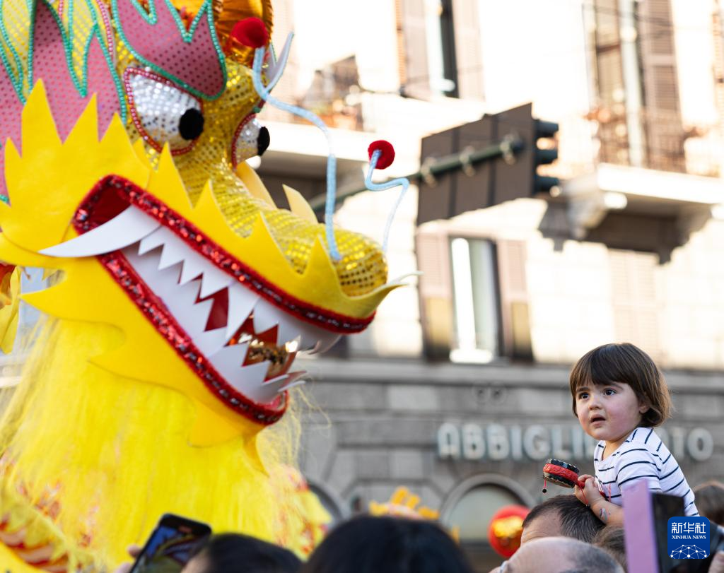 2月18日，在意大利羅馬，一名小朋友在彩妝巡游上觀看舞龍。新華社記者 李京 攝