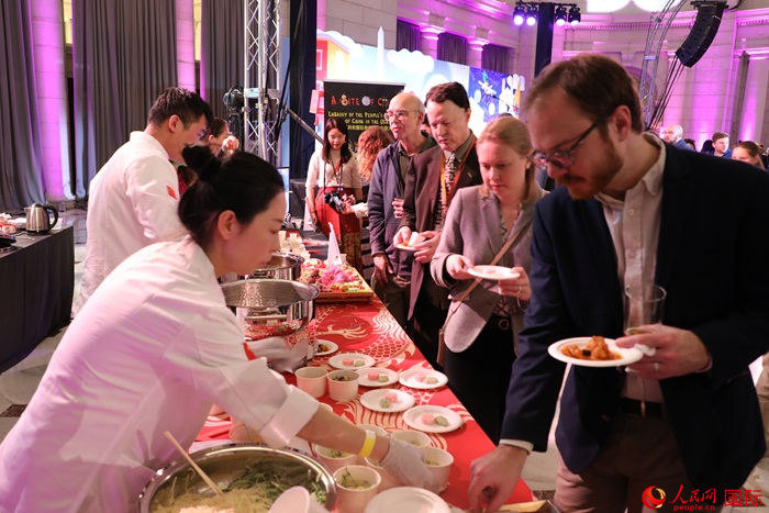 當?shù)貢r間3月7日晚，華盛頓聯(lián)合車站廣場舉行駐美使團“使館主廚挑戰(zhàn)賽”。圖為當?shù)孛癖娫谥袊古_前體驗中國美食。人民網(wǎng)記者 李志偉攝