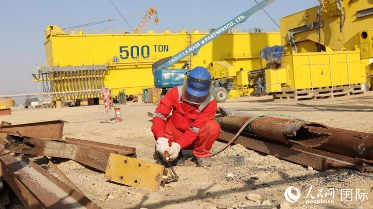 工人正在龍門吊吊裝現(xiàn)場切割金屬件。人民網(wǎng)記者管克江攝