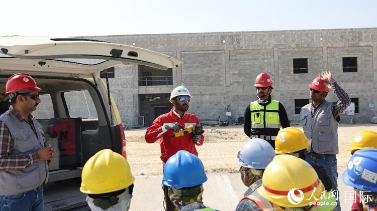 穆薩瓦爾(圖中紅衣人）現(xiàn)場演示工具操作規(guī)范。人民網(wǎng)記者 管克江攝