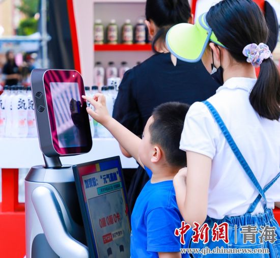 圖為一名小朋友正在和機(jī)器人“志愿者”進(jìn)行互動(dòng)。 沐聞 攝