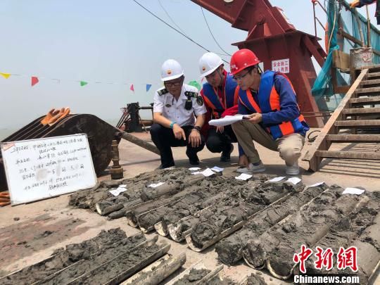 圖為勘察設(shè)計人員與海事局工作人員查看巖芯情況?！∥赫?攝