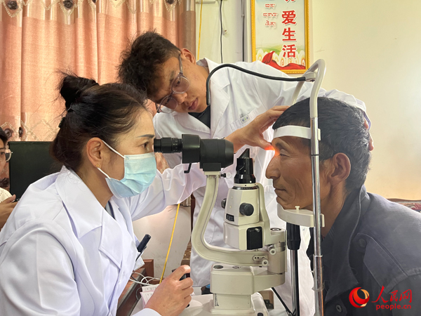 王紅英（左）和團(tuán)隊(duì)成員為達(dá)熱村村民檢查眼睛。人民網(wǎng)記者 杜燕飛攝