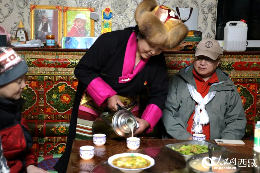 扎西曲登社區(qū)的居民在家中熱情招待遠道而來的游客。居民身著盛裝，為游客倒上熱騰騰的酥油茶，桌上擺放著切瑪與特色美食，賓主共話民族團結(jié)情誼。人民網(wǎng)記者 吳雨仁攝