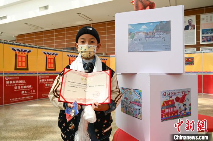 圖為一名獲獎學(xué)生與自己的繪畫作品合影?！≮w朗 攝