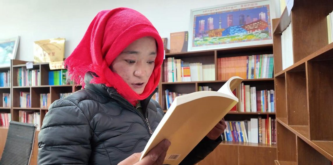 一名婦女正在認真閱讀書籍。申扎縣融媒體中心供圖
