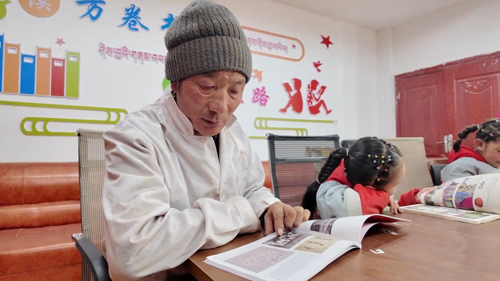 一位當?shù)卮迕窈秃⒆觽冊谀良視堇锉M情享受閱讀時光。申扎縣融媒體中心供圖