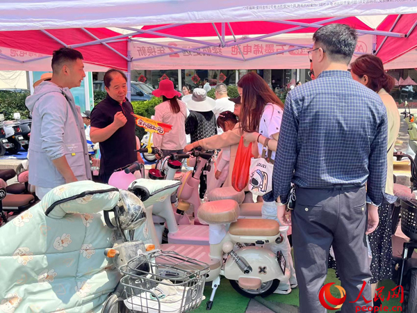 某電動(dòng)自行車品牌工作人員向消費(fèi)者介紹以舊換新相關(guān)情況。人民網(wǎng)記者 杜燕飛攝