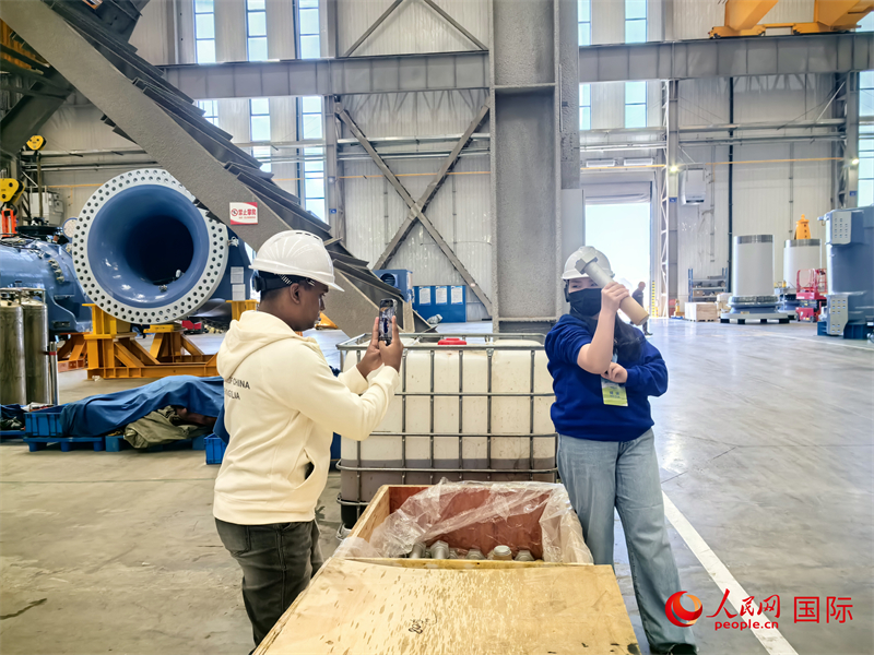 外媒記者掂量廠房?jī)?nèi)的巨型螺栓。人民網(wǎng) 楊春燕攝