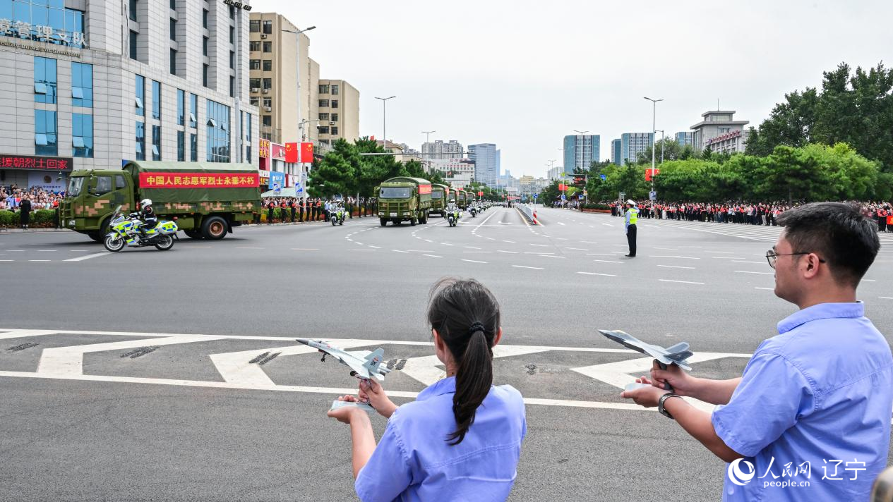 航空工業(yè)沈飛的青年技術(shù)人員拿著受閱戰(zhàn)機(jī)的模型迎接烈士遺骸。航空工業(yè)沈飛供圖
