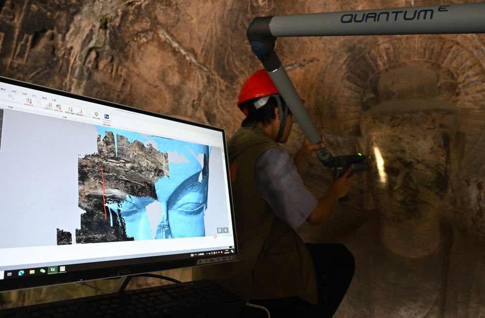 2025年4月9日，武漢大學(xué)文化遺產(chǎn)智能計(jì)算實(shí)驗(yàn)室團(tuán)隊(duì)成員在魏字洞使用關(guān)節(jié)臂掃描儀對佛像進(jìn)行數(shù)字化掃描。圖片來源新華社