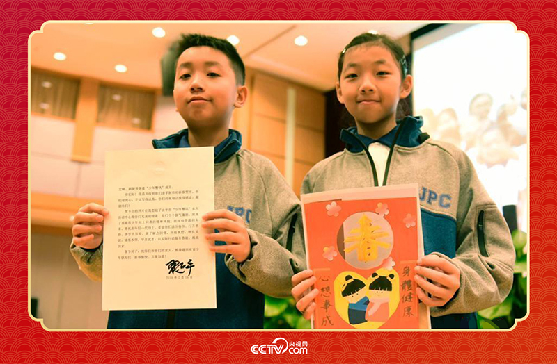 圖為香港“少年警訊”成員郭宏晞（左）展示習(xí)主席回信、羅顥凝（右）展示送給習(xí)主席的賀卡并合影。