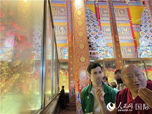 7月25日，省級非物質(zhì)文化遺產(chǎn)項(xiàng)目塔爾寺酥油花的代表性傳承人朋措堅(jiān)參（右）在塔爾寺酥油花館講解酥油花的制作過程。人民網(wǎng) 謝瑩攝