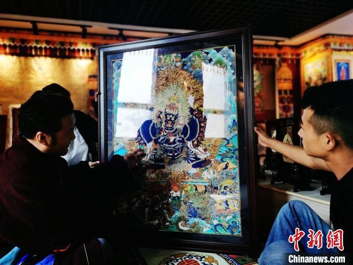 圖為久美尖措(左)與徒弟們展示唐卡作品?！?zhí)砀?攝