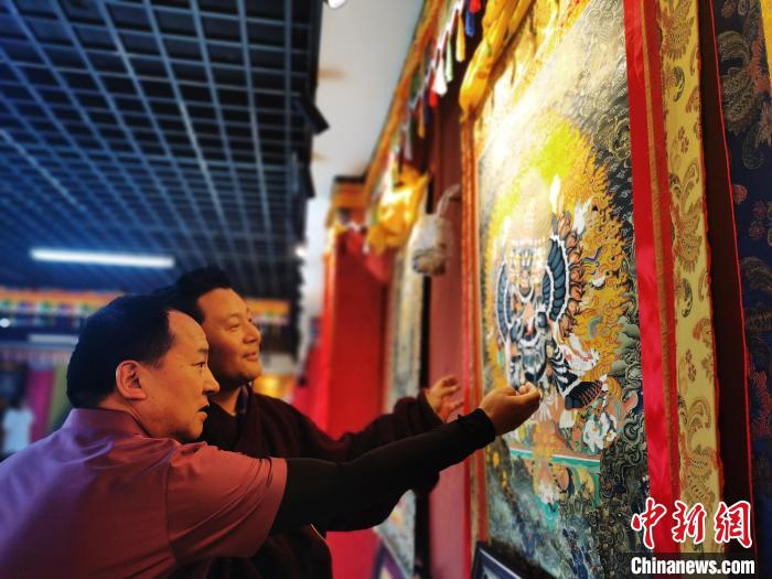 圖為久美尖措展示唐卡作品?！?zhí)砀?攝
