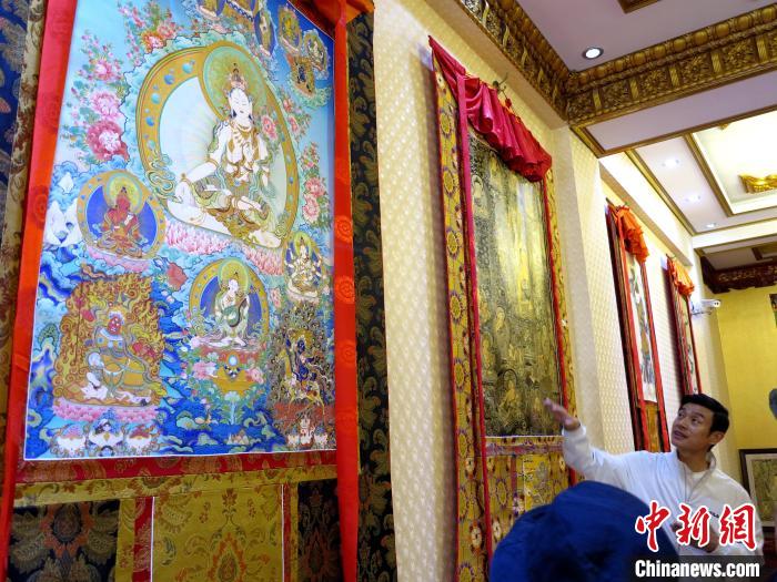 圖為完德尖措展示熱貢龍樹畫苑內(nèi)的唐卡?！?zhí)砀?攝