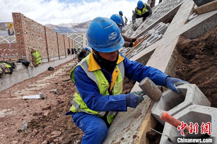 圖為光伏發(fā)電項(xiàng)目施工區(qū)工人在護(hù)坡鋪設(shè)空心磚?！±铍h 攝