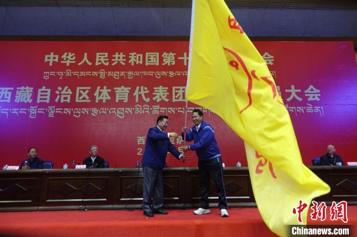 西藏自治區(qū)副主席甲熱·洛桑丹增授代表團(tuán)團(tuán)旗，西藏自治區(qū)體育局局長尼瑪次仁接旗。　冉文娟 攝