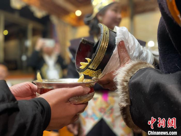 圖為主人在碗中斟滿青稞酒?！∪轿木?攝