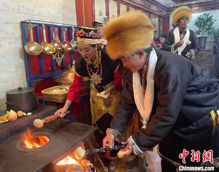 圖為人們在火上烤節(jié)日美食“結(jié)達”?！∪轿木?攝