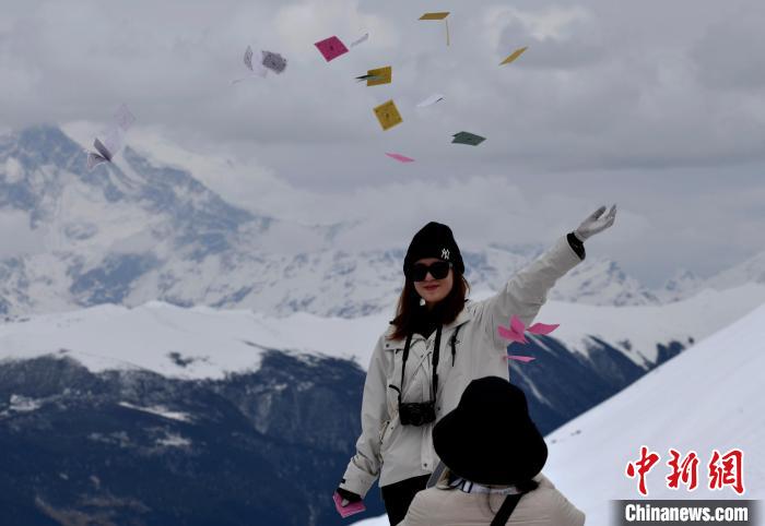 圖為5月14日，游客在西藏林芝色季拉山觀景臺拋灑“隆達(dá)”(風(fēng)馬旗，藏族民眾的一種祈福方式)?！±盍?攝