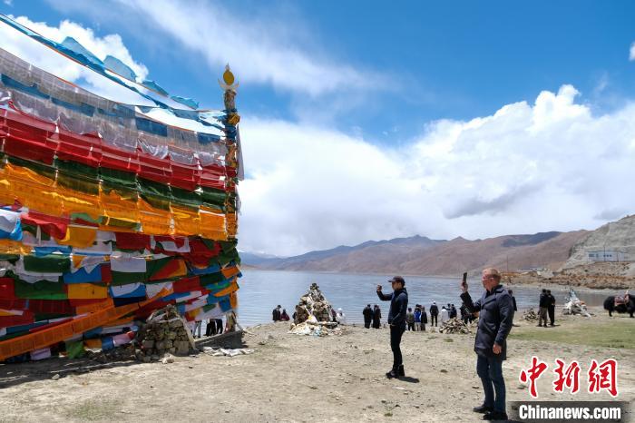 進藏參訪嘉賓在羊湖畔拍攝經(jīng)幡。　江飛波 攝