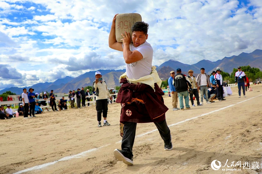 來(lái)自拉薩市當(dāng)雄縣的牧民選手將一塊150斤重的石頭扛在肩上飛奔。