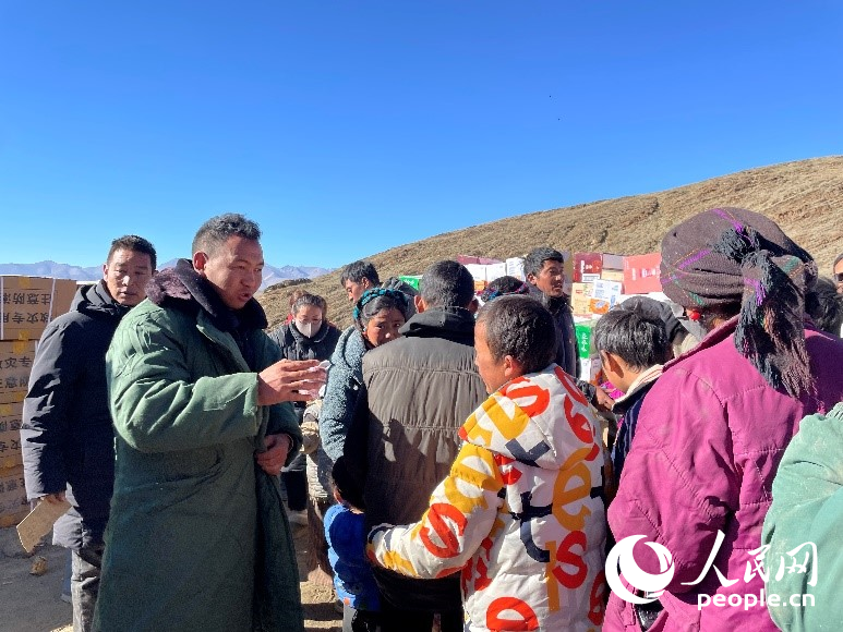 定日縣公安局干警頓珠次仁（左二）正在協(xié)助分發(fā)物資。人民網(wǎng)記者 郝潔攝