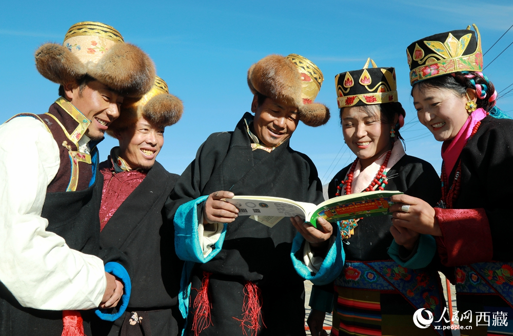 鄉(xiāng)親們身著民族盛裝，圍站在一起認真翻看日歷，共話農(nóng)事安排與時節(jié)規(guī)律，笑容洋溢傳遞豐收期盼。人民網(wǎng)記者 吳雨仁攝