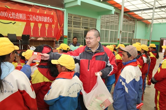 段玉平為孩子們分發(fā)愛(ài)心人士捐贈(zèng)的新華字典 圖片來(lái)源：央廣網(wǎng).jpg